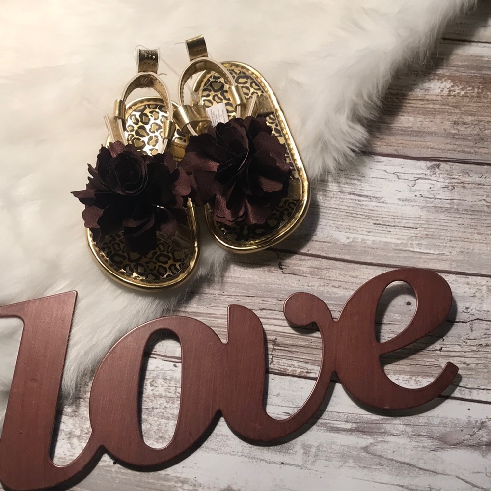 Gold Sandals with brown flower on top of toes.